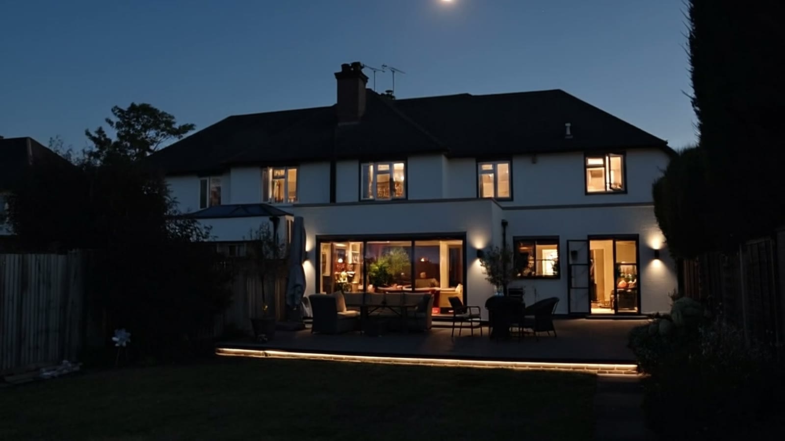Finished whole-home renovation and single-storey extension at twilight with patio and garden